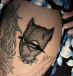 a woman's thigh with tattoos on it and an image of a cat in the background