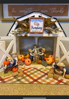 a table with pumpkins and figurines in front of a sign that says thanksgiving