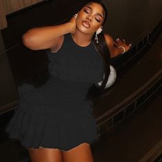 a woman in a black dress posing for the camera with her hand on her head