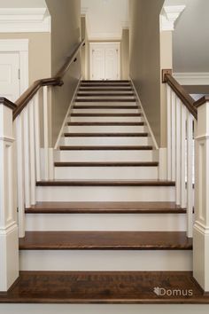 a set of stairs leading up to the second floor in a home with white walls and wood handrails