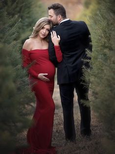 a pregnant woman in a red dress standing next to a man