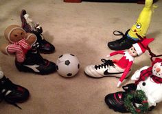 several stuffed animals are sitting on the floor next to soccer balls and tennis shoes with christmas decorations around them