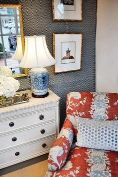 a living room filled with furniture next to a dresser and lamp on top of a table