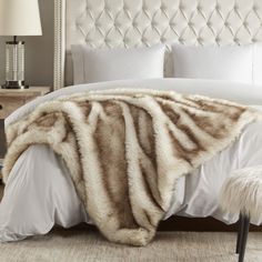 a white bed with a fur blanket on top of it