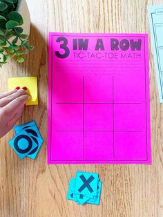 a person is playing with three in a row game on a table next to a potted plant