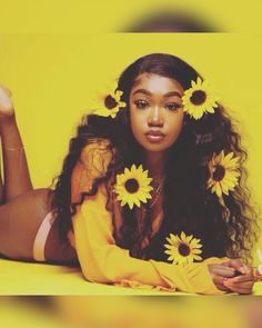 a woman laying on the ground with sunflowers in her hair