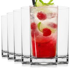 four glasses filled with different types of drinks and garnished with limes, raspberries, and lemon wedges