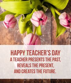 a vase filled with pink flowers sitting on top of a wooden table next to a sign that says happy teacher's day