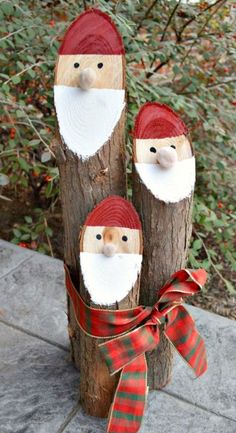 three wooden logs with santa claus faces on them and a red ribbon tied around the ends