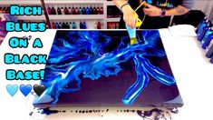 a man is painting blue flames on a black base with acrylic inks