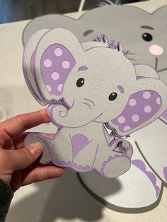 a person holding up a cut out of an elephant