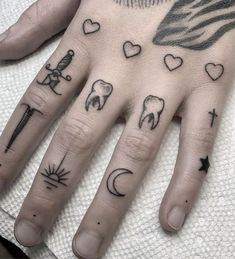 a person's hand with tattoos on it and other things in the middle of their fingers