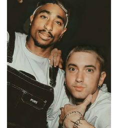 two men posing for the camera with tattoos on their arms