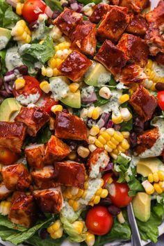 a salad with chicken, avocado, tomatoes and corn on it is shown