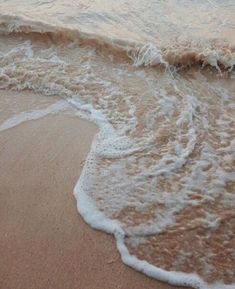 the waves are rolling in on the beach sand and water is crashing onto the shore