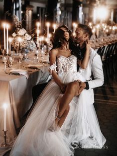 a man and woman are sitting at a table with candles in the room behind them