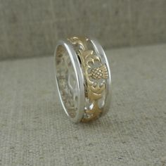 two gold and silver wedding bands with an intricate design on the side, sitting on a carpeted surface