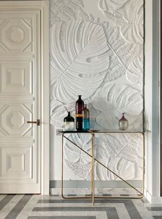 a white door and some bottles on a table in front of a wallpapered room