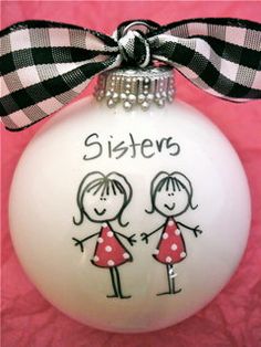 a white ornament with a black and white ribbon on it that says sisters