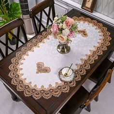 a table with flowers in a vase on it and lace doily around the table