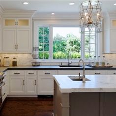 a large kitchen with white cabinets and marble counter tops, an island in the middle