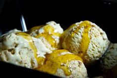 three scoops of ice cream in a black container with yellow and white icing