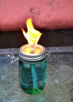 a green mason jar with fire inside sitting on a table