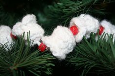 crocheted ornaments are hanging from the branches of a christmas tree, which is decorated with red and white beads