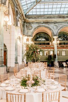 the tables are set up for a wedding reception in an ornate building with high ceilings and chandeliers