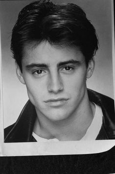 a black and white photo of a man in a leather jacket looking at the camera