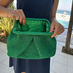 a woman holding a green purse in her hand