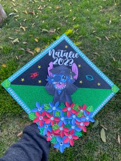 someone is holding up a graduation cap decorated with an image of a dog and flowers