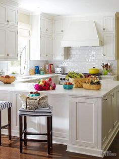 a kitchen filled with lots of white cabinets and counter top next to a bar stool