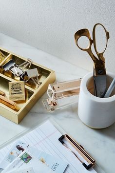 an assortment of office supplies sitting on a desk next to a cup and pen holder