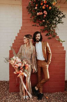 a man and woman standing next to each other in front of a red brick wall