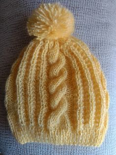 a yellow knitted hat with a pom - pom on top