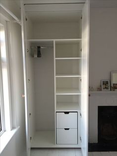 a white closet with shelves and drawers next to a fire place in a room that is painted white