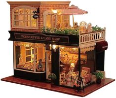 a doll house is set up to look like a coffee and cake shop with flowers on the roof