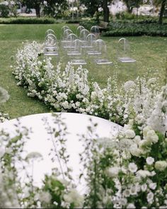 rows of chairs and tables with white flowers in the foreground, surrounded by green grass