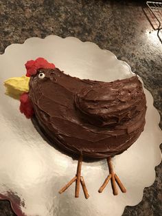 a cake shaped like a chicken sitting on top of a white plate with brown icing