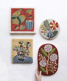 four handmade coasters with flowers and plants on them, one being held up by a person