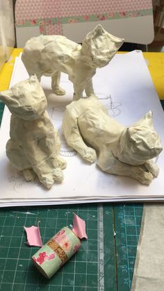 three paper mache animals on top of a piece of crafting paper next to a roll of tape