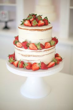 a three tiered cake with strawberries on top