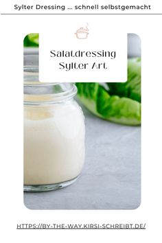 a glass jar filled with salt sitting on top of a table next to lettuce