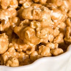 a bowl filled with caramel popcorn sitting on top of a table