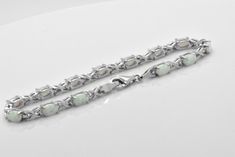 Here we have a beautiful lab created White Opal Sterling Silver tennis Bracelet. Opals feature cabochon oval cut in prong setting. Bracelet is about 5 carats of gemstone total weight. This bracelet was designed to allure and impress. It will be an excellent addition to a jewelry collection due to its unique design. The bracelet is made out of solid 925 Sterling Silver and 14k white gold overlay for that timeless and classic look. Brand new item, never worn. Other lengths available per especial r Oval Sterling Silver Bracelet In Fine Jewelry Style, Fine Jewelry Sterling Silver Oval Bracelet, Oval Cabochon Bracelet In Fine Jewelry Style, Oval Cabochon Bracelets For Formal Occasions, Oval Cabochon Bracelets Fine Jewelry, Oval Cabochon Bracelet Fine Jewelry, Luxury Silver Bracelets With Cabochon, Fine Jewelry Cabochon Bracelets As Gift, Oval Cabochon White Gold Jewelry