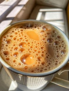 there is a cup of coffee on the window sill with an egg in it