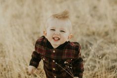 a little boy that is standing in the grass with his mouth open and smiling at the camera