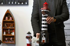 a man is holding a model lighthouse made out of legos and other items in his hands