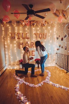 a man kneeling down next to a woman in front of a sign that says will you marry me